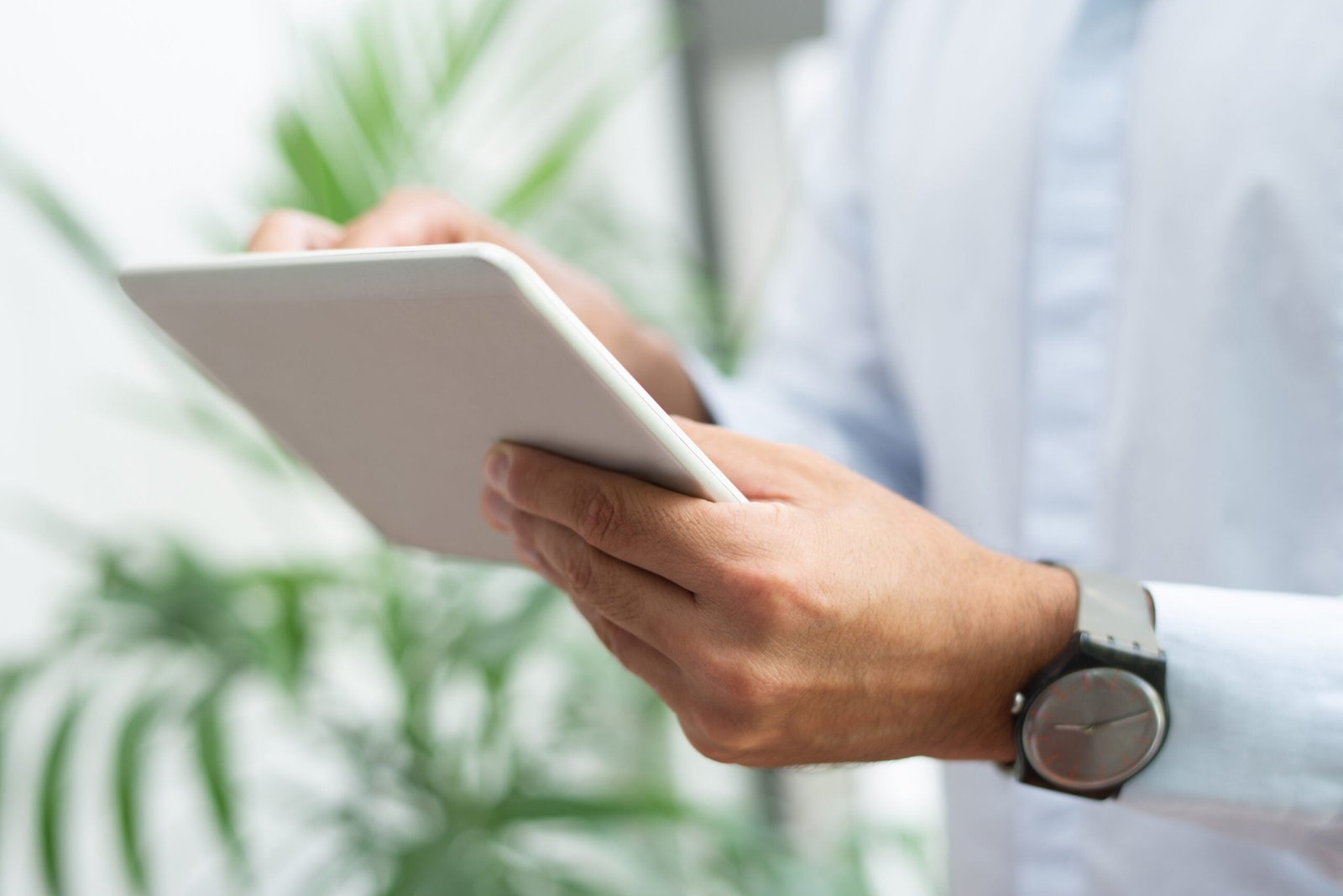 Close-up of businessman with wristwatch using tablet