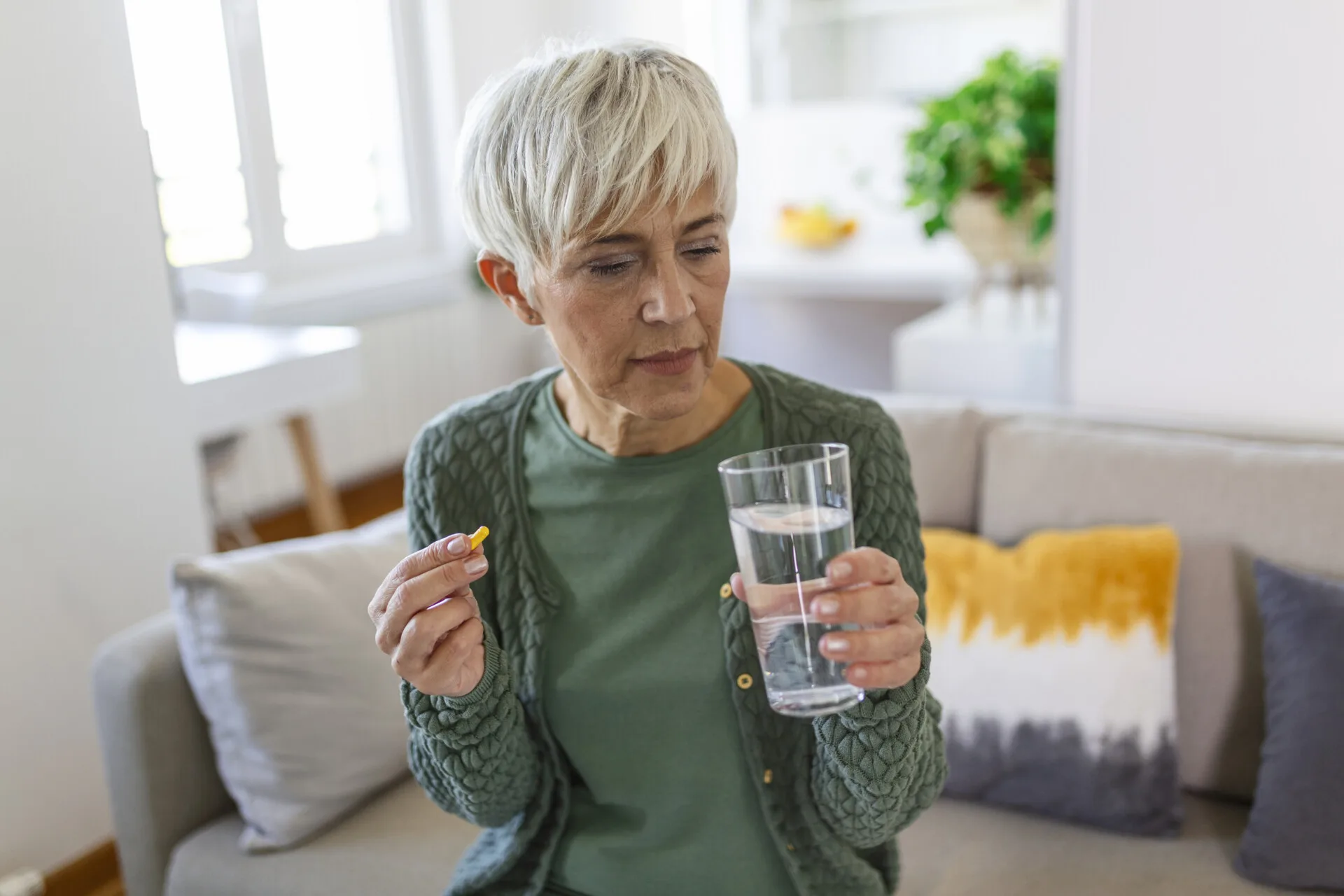 senior-woman-takes-pill-with-glass-water-hand